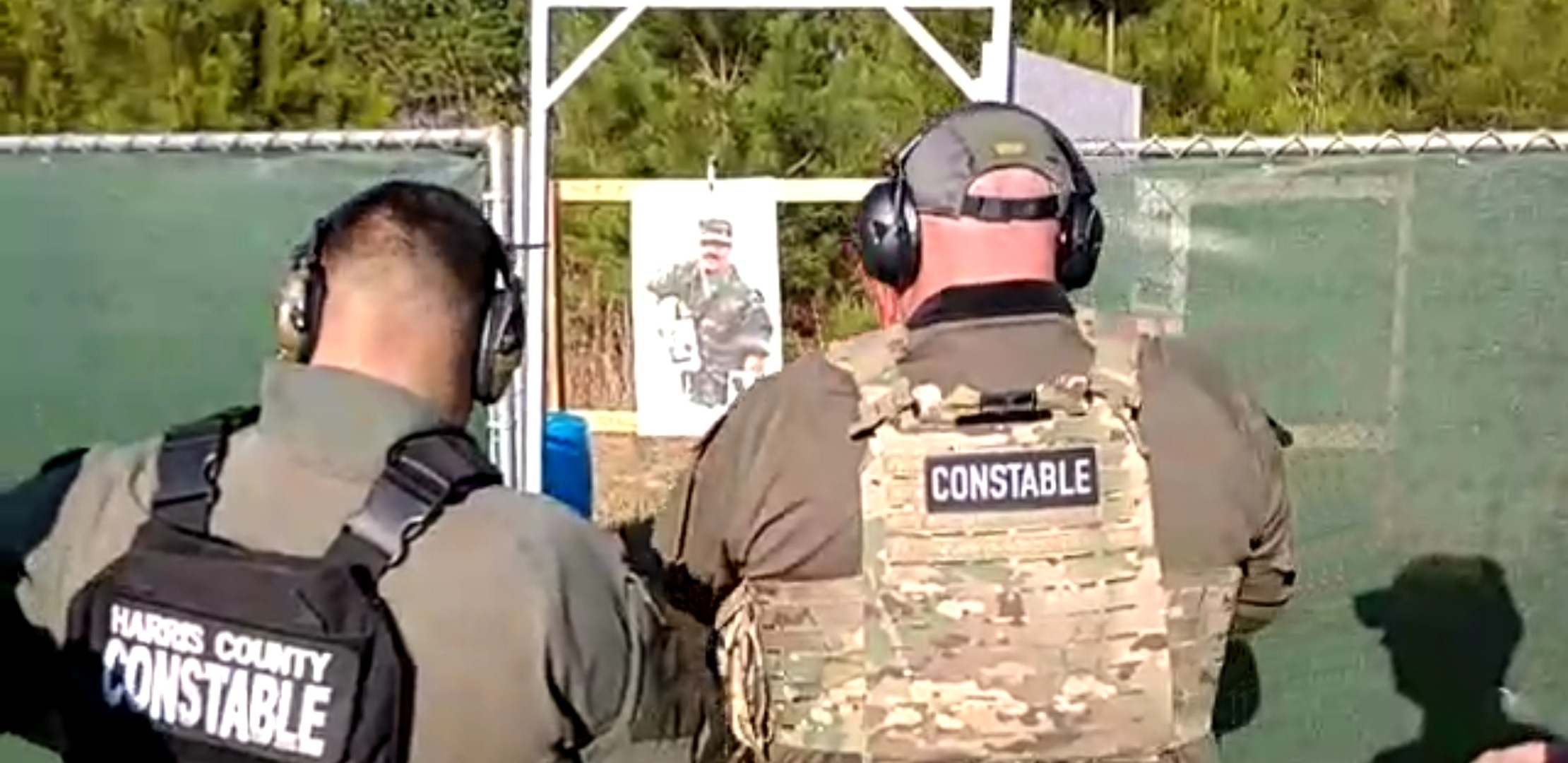 Two uniformed constables at a shooting range aim at a target.